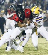 Hanford's Noah Noyola gets tackled by a pair of Tiger defenders in Friday night's loss to Hanford High School in Neighbor Bowl.